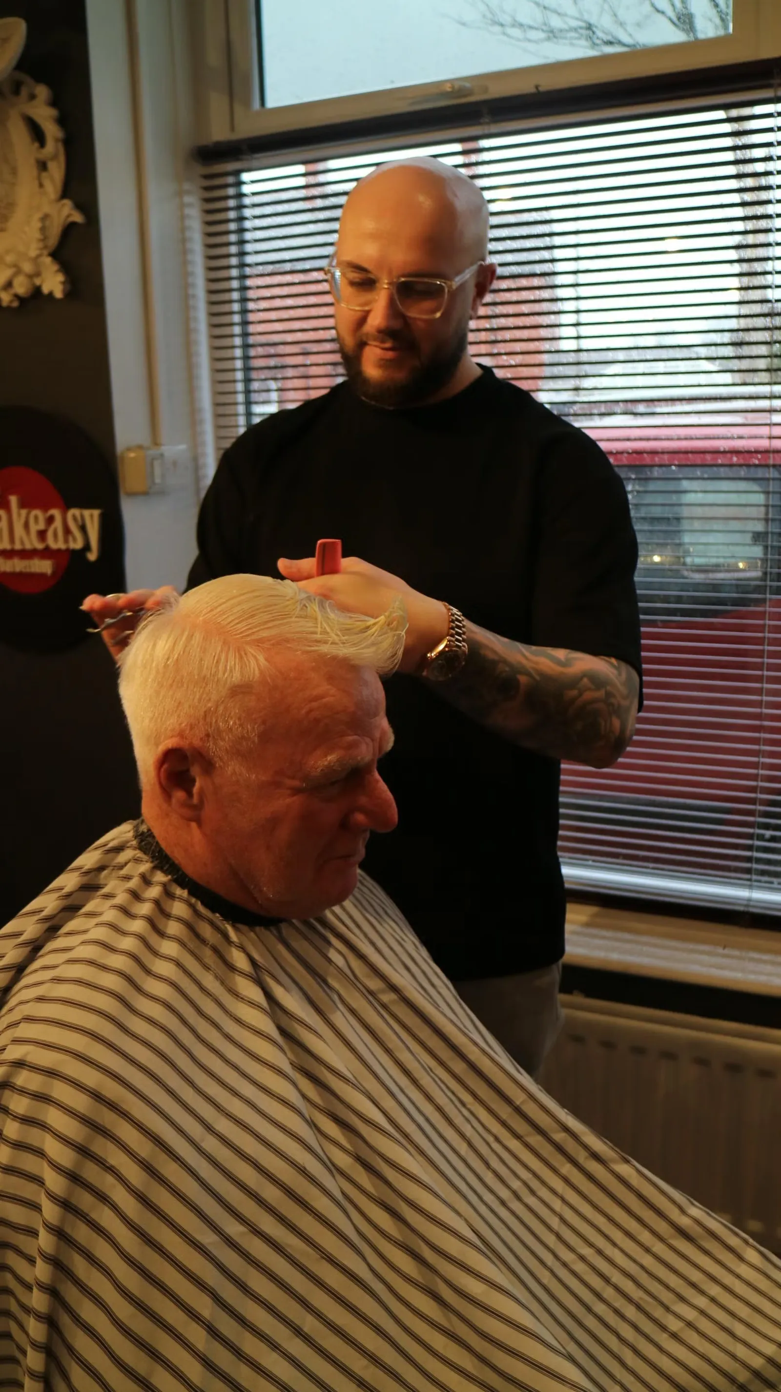 Finishing an older gentleman's cut by the window